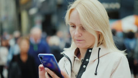 a sad middle-aged woman uses a smartphone in a crowd of people loneliness and depression concept