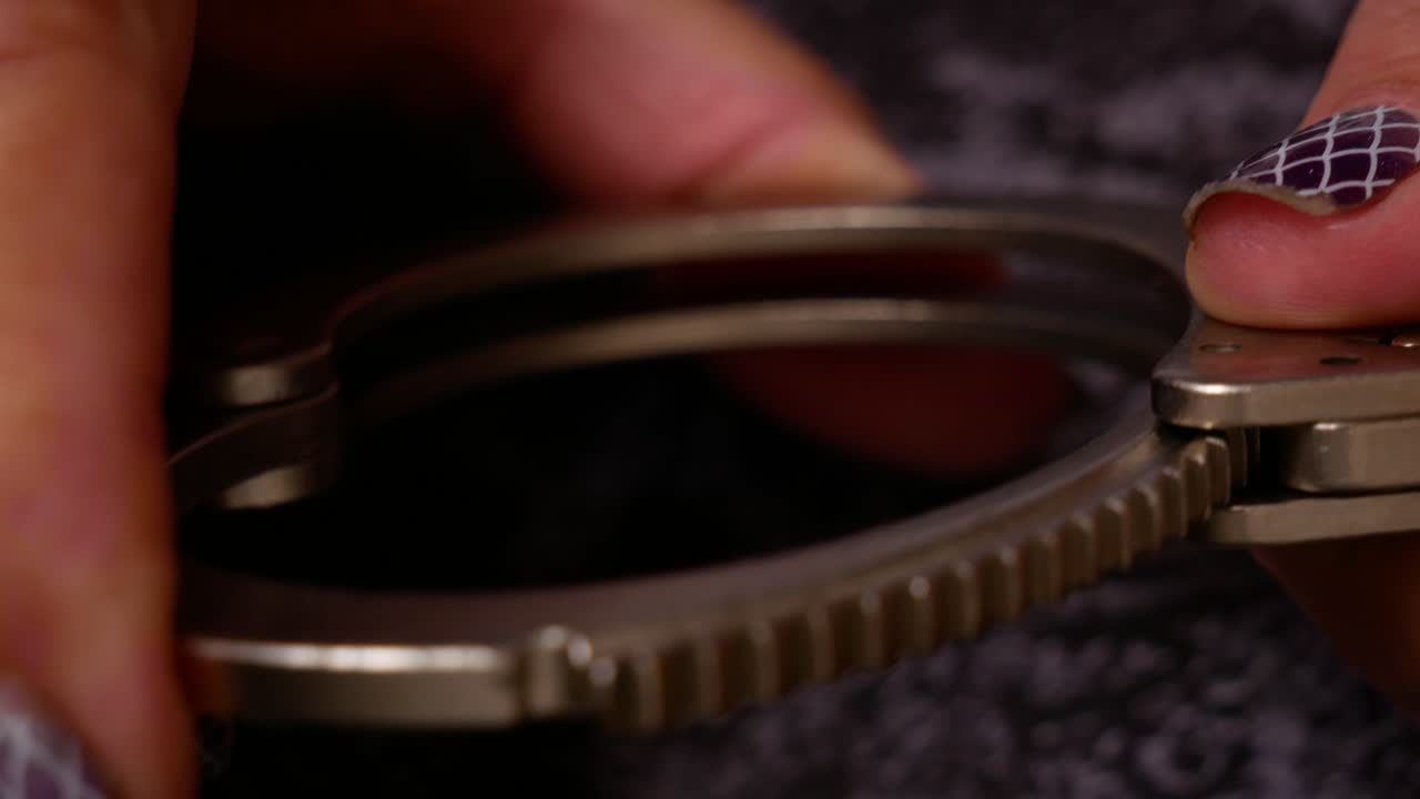 elegantes manos de mujer mayor trabajando con un par de esposas de metal de la policía