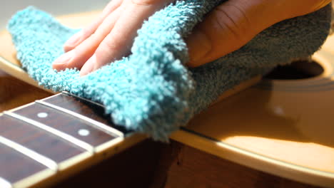 musician cleaning and oiling an acoustic guitar fretboard