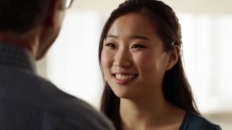 a young woman engages in an animated discussion with an older man, both smiling and enjoying each other's company in a comfortable indoor environment.