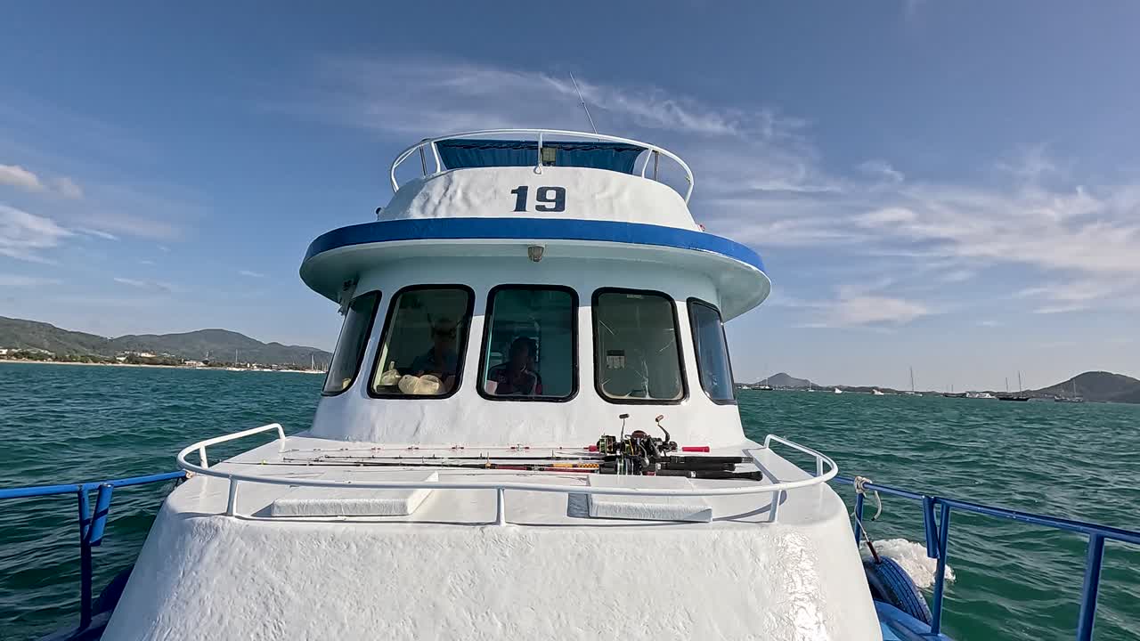 A fishing boat navigates the ocean near Phuket, Thailand, under clear skies with gentle camera panning