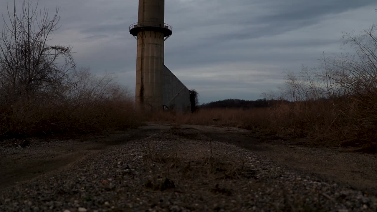 Slider dolly shot on desolate trail leading to large silo. Empty barren path in middle of nowhere
