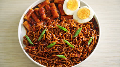 jjajang rabokki - fideos instantáneos coreanos o ramyeon con pastel de arroz coreano o tteokbokki y huevo en salsa de frijol negro - estilo de comida coreana