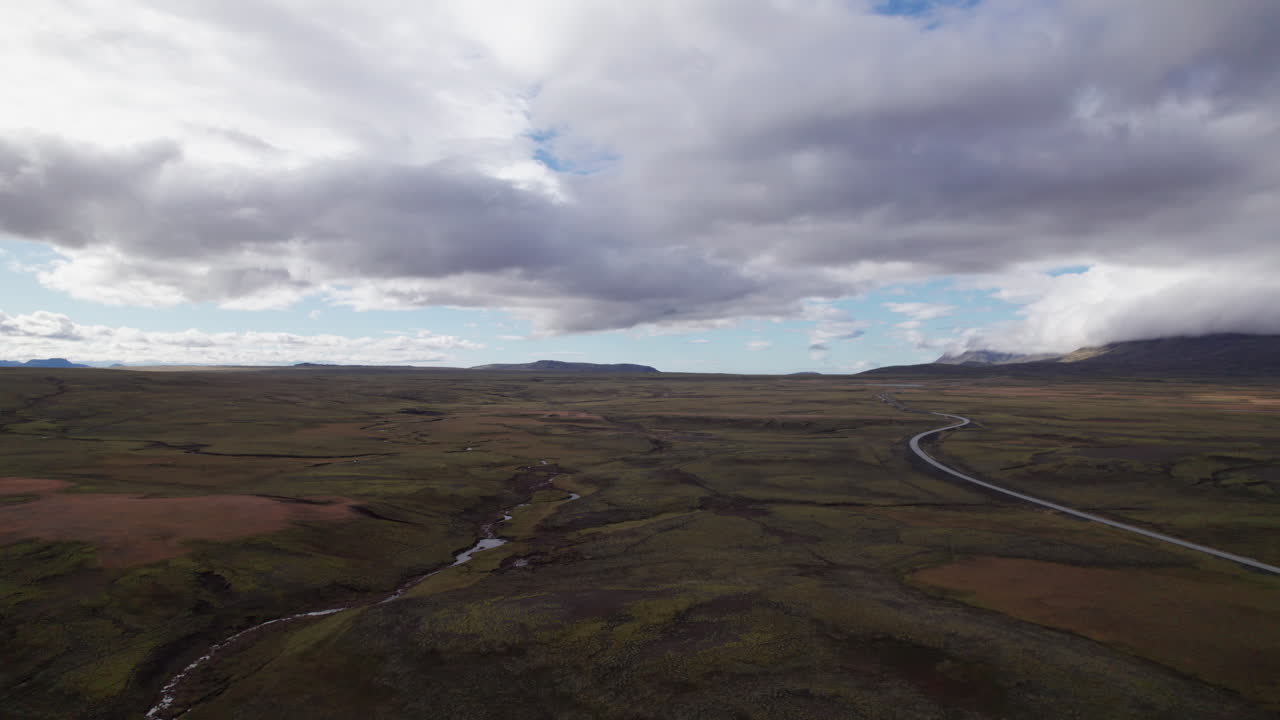 Uma estrada sinuosa vazia e um riacho perto do Parque Nacional Thingvellir, na Islândia Central, Vista Aérea.