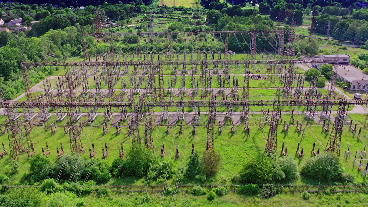 High voltage steel pylons in green field. View from above the power transmission lines. Electric tower line among nature. Aerial view.