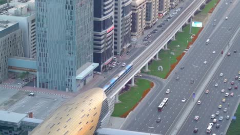 Dubai-Skyline,-Trains-Arriving-At-The-Dubai-Metro-Station-With-Cars-Travelling-In-Sheikh-Zayed-Road-In-Dubai,-United-Arab-Emirates-At-Daytime