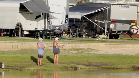 a pair fishing by water near rv campsite