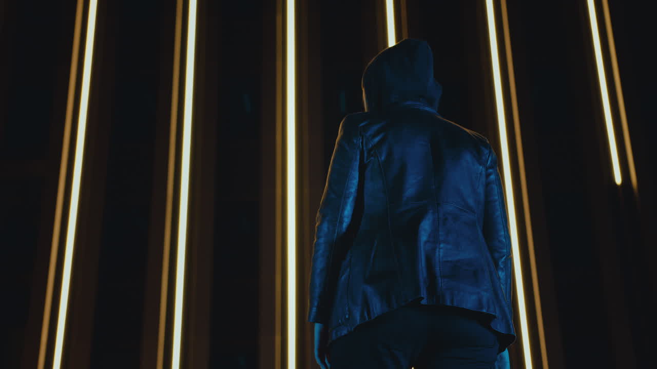 mujer encapuchada entra a tiro, levanta los brazos y se estira