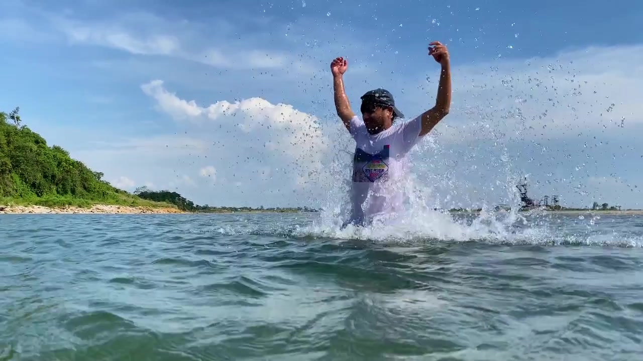 Fiume sereno, ragazzo che emerge dall'acqua con un salto creando un grande schizzo. Scenografico cielo blu con nuvole soffici