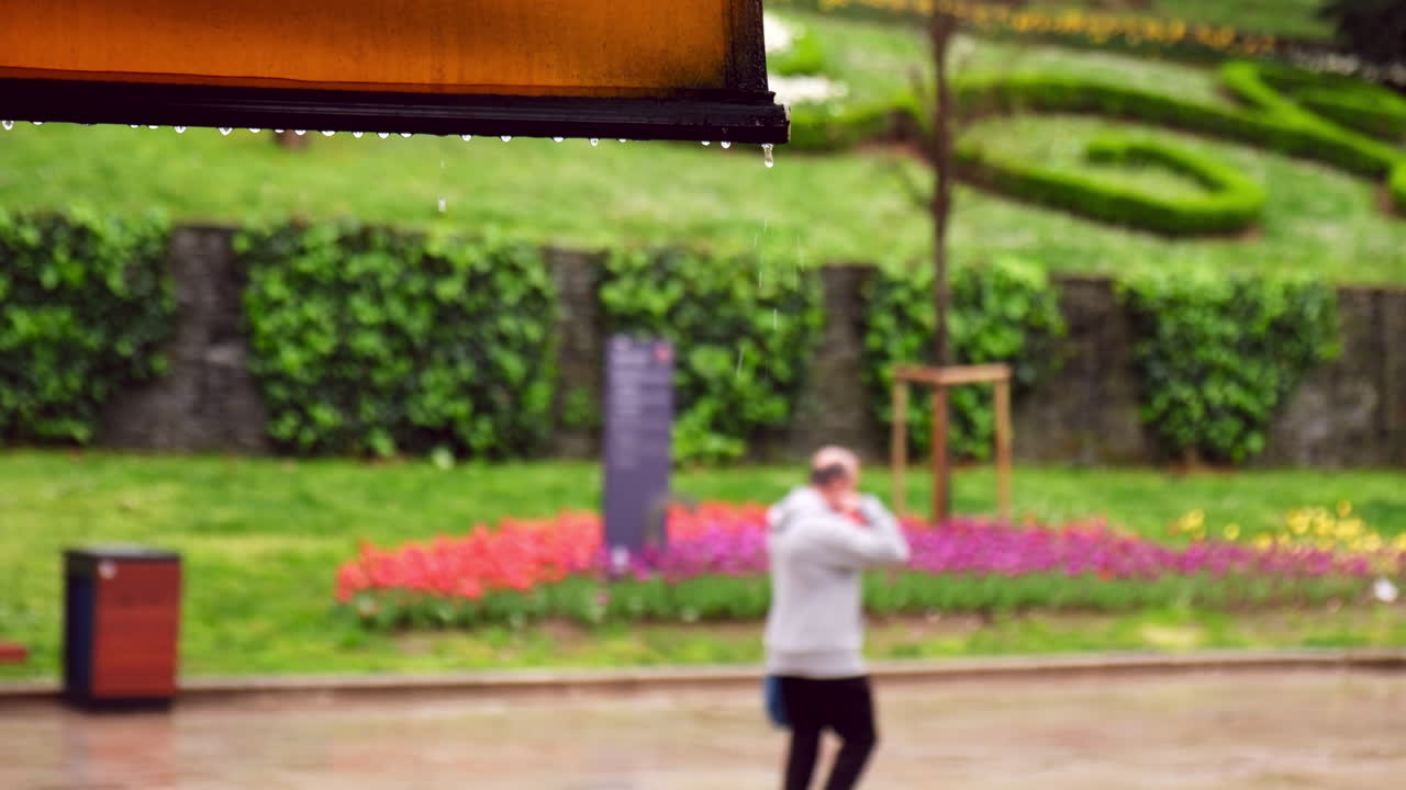 한 남자가 슬로우 모션으로 이스탄불의 굴하네 공원에서 비를  ⁇ 고 있습니다.