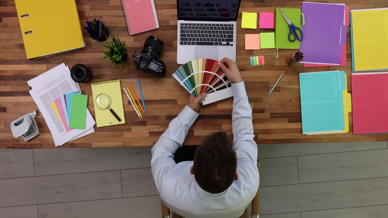 Male employee examines palette of bright colors in office