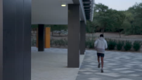 young black man in sportswear takes off his hood and runs outdoors