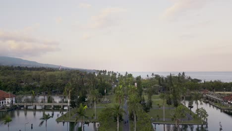 vista aérea, tomada por un dron, de un parque tranquilo con un lago sereno, rodeado de exuberante vegetación y un telón de fondo del océano y una cordillera