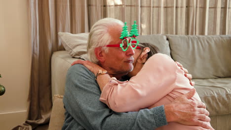 elderly couple hugging warmly at home, wearing festive christmas glasses