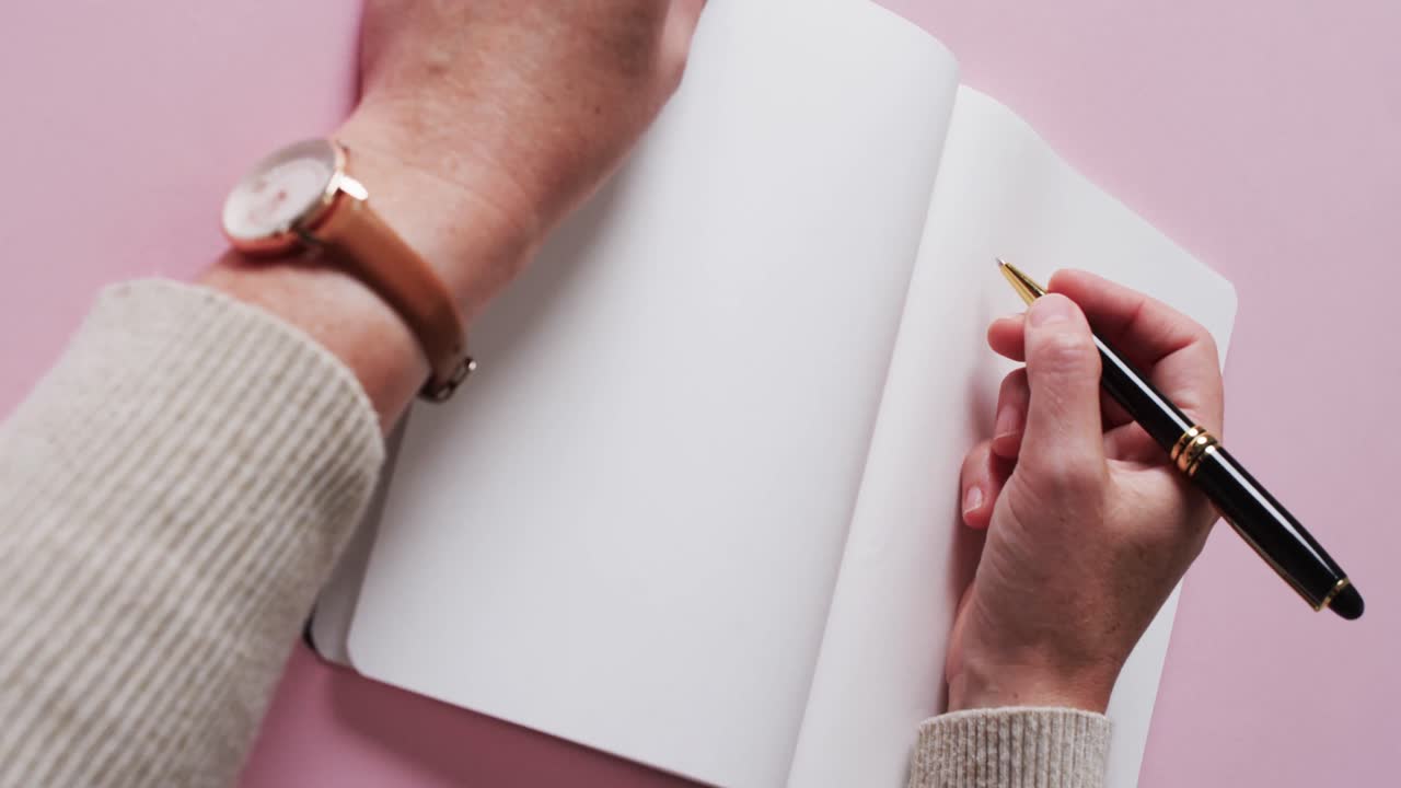 Close up of hand writing with pen on book with copy space on white background in slow motion