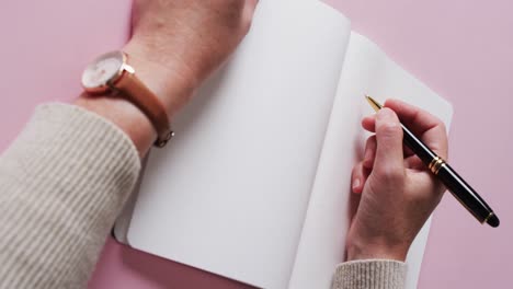 close up of hand writing with pen on book with copy space on white background in slow motion