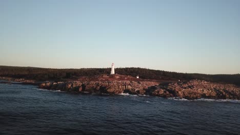 seaside aerial view of lighthouse on rocky coast of island on golden hour