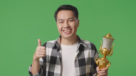 man holding a trophy and giving a thumbs up