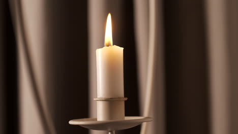 las velas suaves se queman frente a las cortinas con sombras en movimiento, de cerca