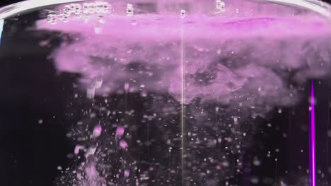 sales de baño carbonatadas rosas caídas en agua con burbujas que se elevan a cámara lenta