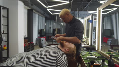 Peluquero-Negro-Recortando-La-Barba-Del-Hombre-Con-Cortapelos