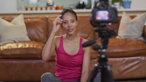 Mixed-race-woman-practicing-yoga,-using-camera-making-vlog
