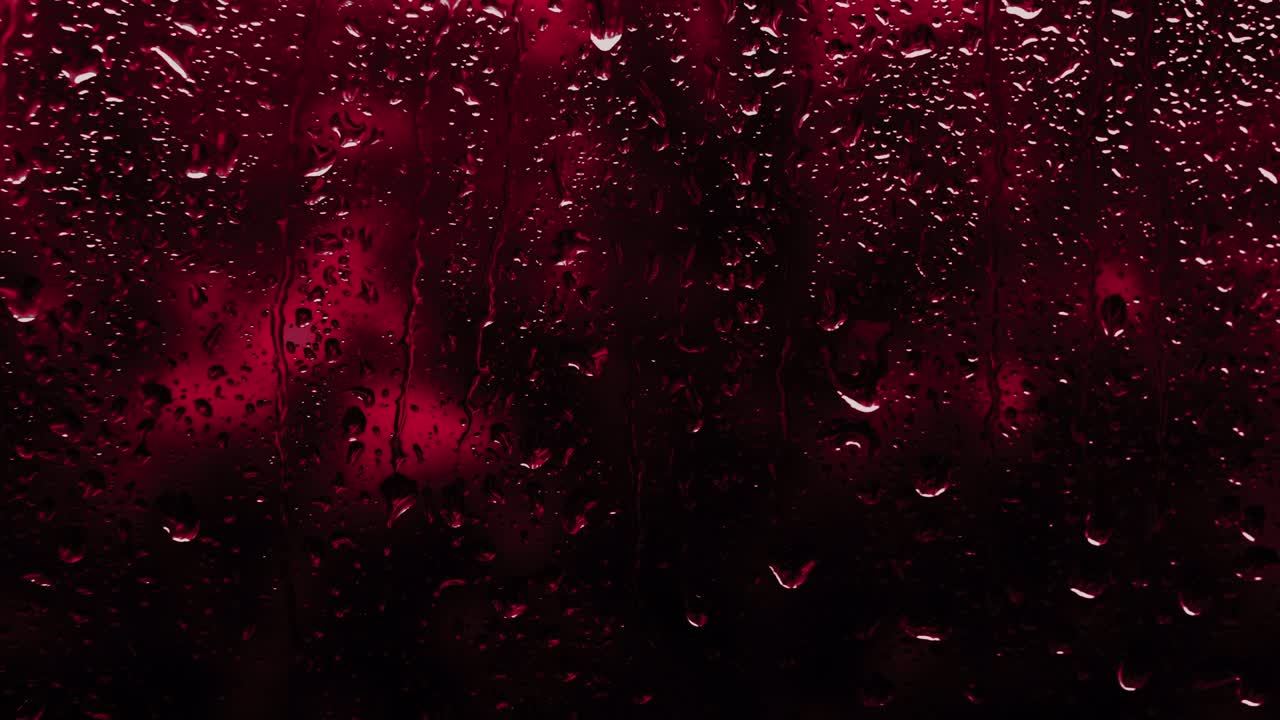 Fond pluvieux en rouge néon, des gouttes coulent sur la vitre, arrière-plan avec espace pour texte. La texture des gouttes de pluie sur le verre
