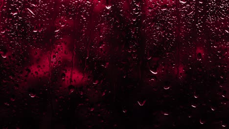 rainy background in neon red, drops flow down the glass, copy space background. the texture of raindrops on the glass