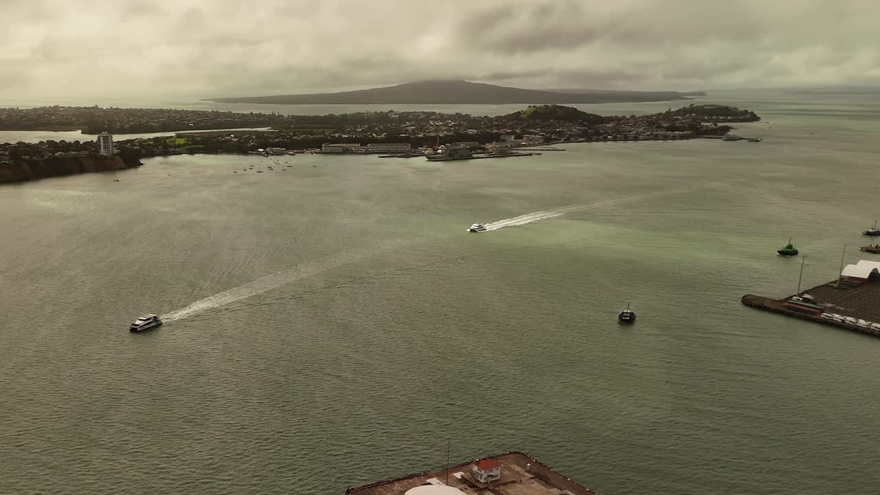 Tourist Ferry arriving port of Auckland City during golden sunset. Aerial panorama view. Cloudy day in summer. Transport of tourism in New Zealand.