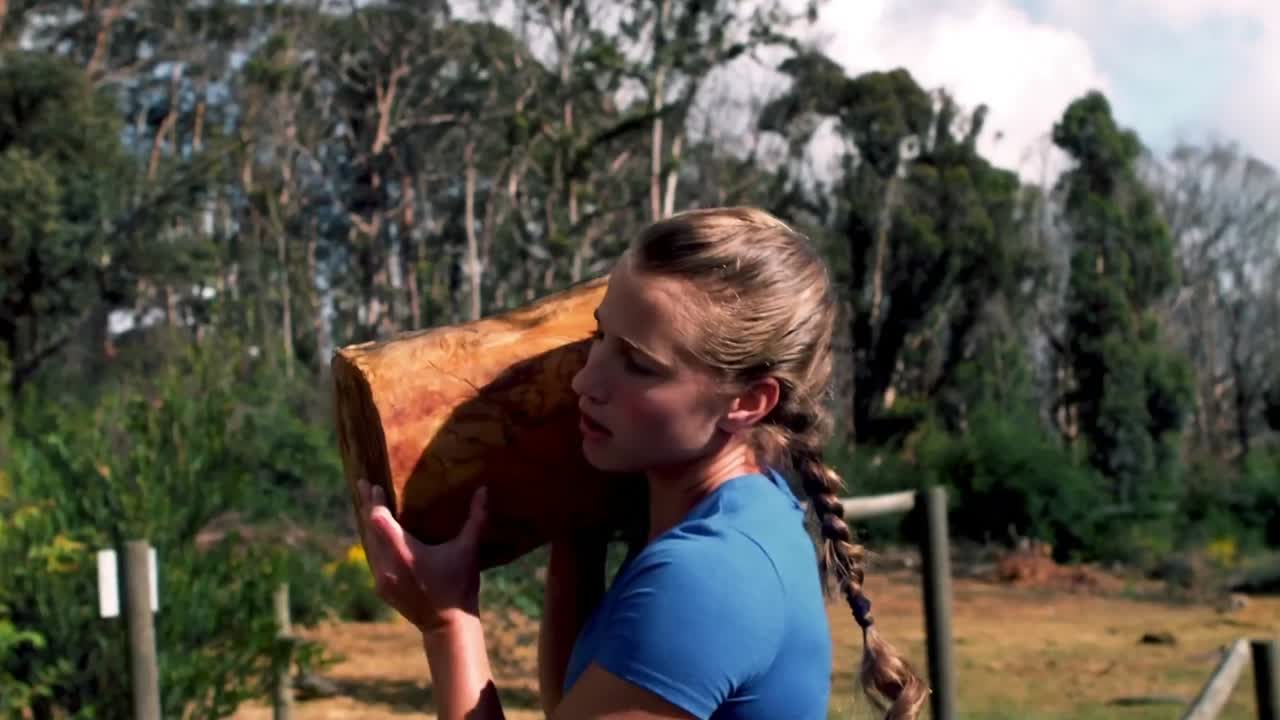 장애물 코스 도중 무거운 나무 로그 를 들어 올리는 여자