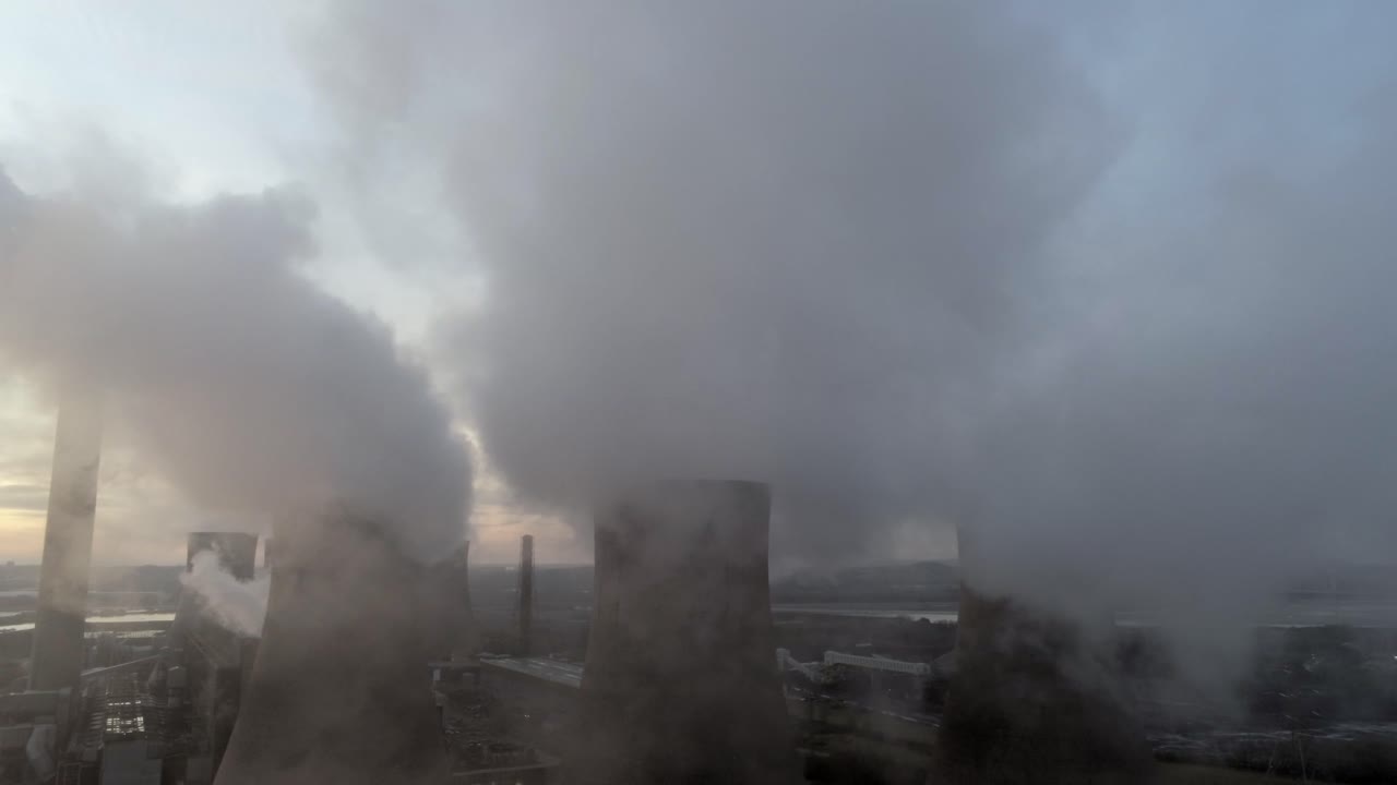Vista aérea elevada de las emisiones de humo y vapor de las torres de refrigeración de una central eléctrica del Reino Unido al amanecer.