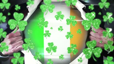 Animation-of-green-clovers-and-man-with-Irish-flag-on-his-t-shirt-in-background-for-world-St.-Patr