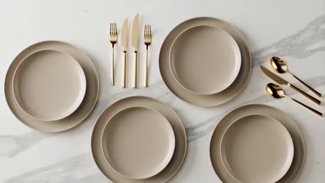 elegant table setting with gold cutlery and beige plates on marble