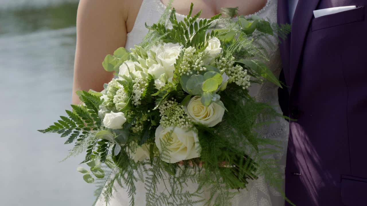 Bouquet da sposa tenuto dalla sposa sullo sfondo di un lago