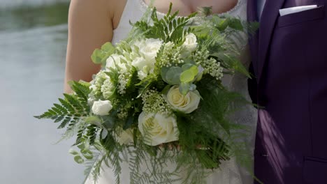 ramo de bodas sostenido por la novia contra un fondo de lago