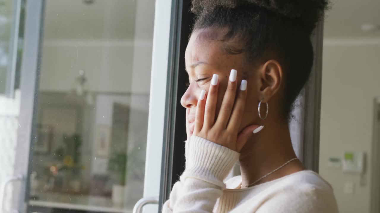 Video of crying african american woman looking outside window
