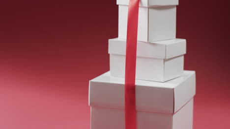 Video-of-stack-of-presents-with-red-ribbon-with-copy-space-on-red-background