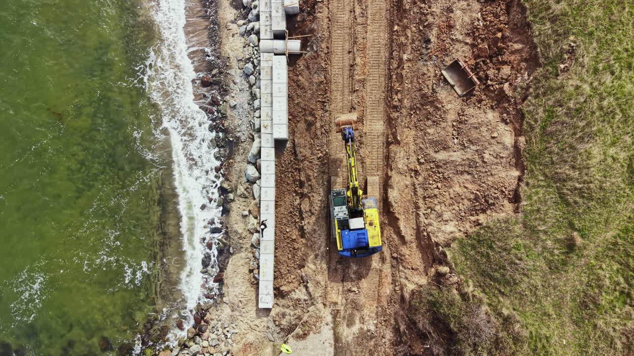 Construction of a sea wall along the shoreline with heavy machinery at work during daylight hours in a coastal area