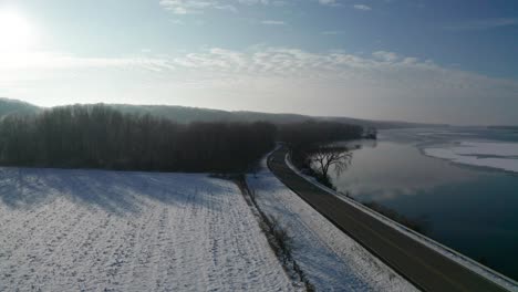 Car-driving-on-scenic-coastal-river-road-during-white-winter-season