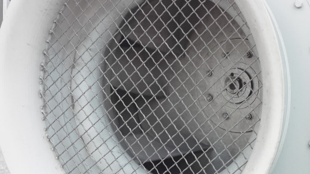 un gran ventilador industrial girando detrás de las rejas