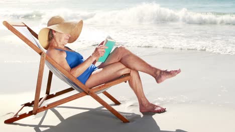 anciana jubilada leyendo un libro mientras está acostada en una silla de cubierta