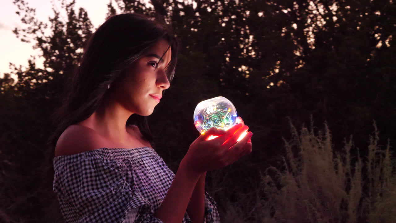 A beautiful woman sorcerer wandering in a fantasy landscape with a magic spiritual orb glowing in illuminated light