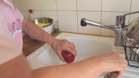 Senior-lady-cooking-at-home-preparing-paprika-in-the-kitchen-sink