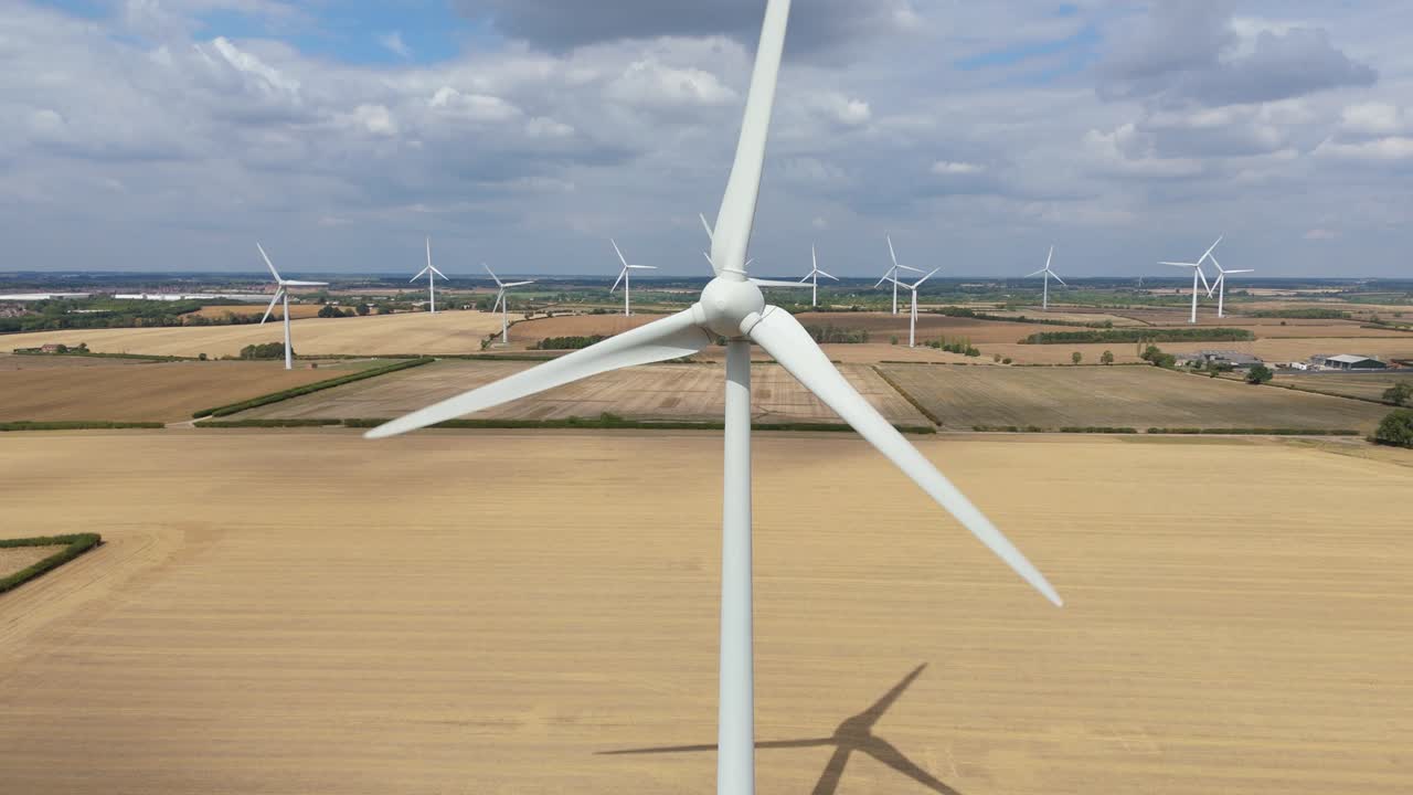 Wide aerial footage of renewable energy turbines in farmland near Burton Latimer England producing clean electricity for sustainable development