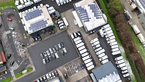 solar panels on roof of camper van car dealership during cloudy day in industrial area. driving cars on intersection road. aerial top down shot.