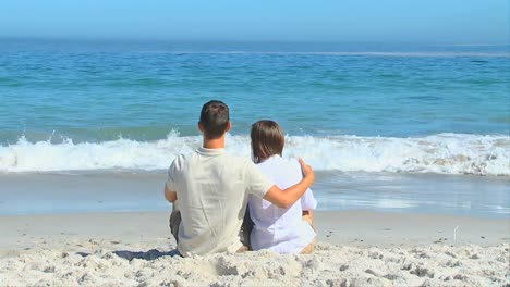 cute couple hugging sitting in front of the sea