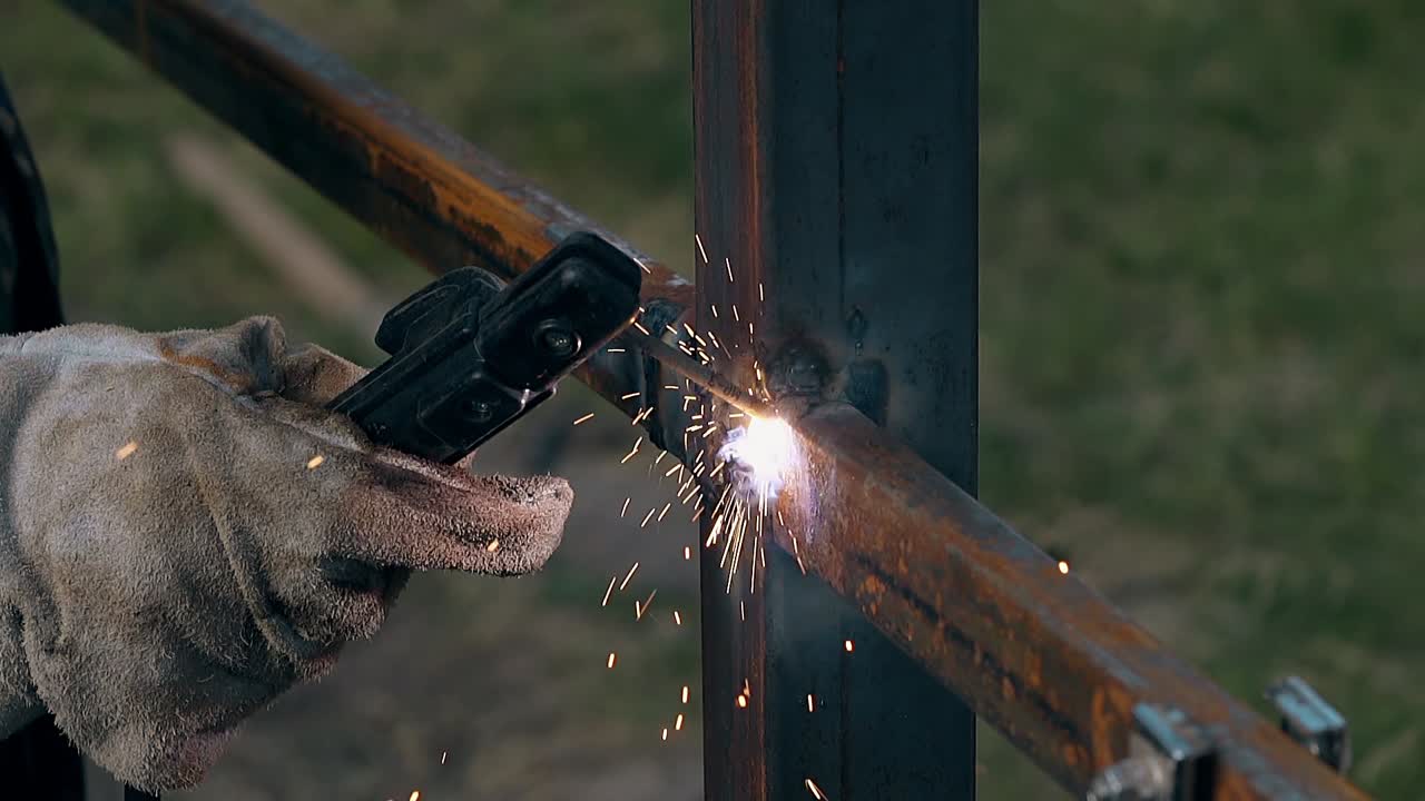 un soldador de vista cercana construye una valla con tablas usando una herramienta moderna