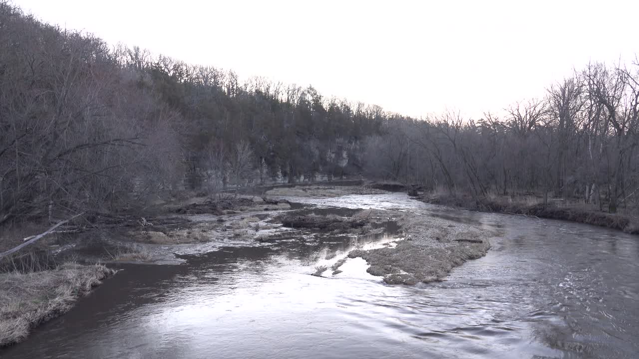 Rustige rivier die stroomt door een kaal winters boslandschap