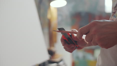 de las manos del artista afilando el lápiz con un cuchillo