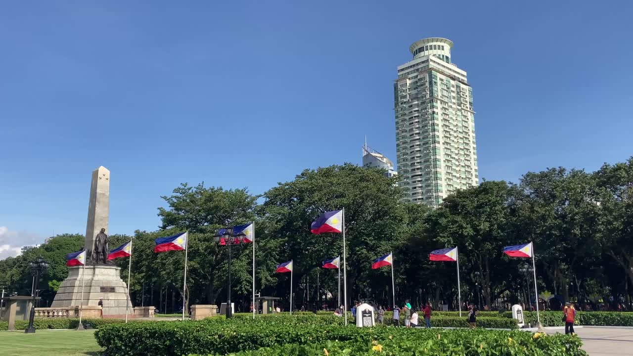 Wide view of the Rizal monument with Philippine flags in Luneta Park, Manila